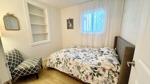 A bedroom with a bed, a chair, a window, and a mirror. - Bright & Cozy Retreat Near Shops & Subway (North York)