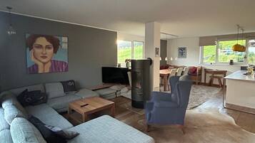 Ein modernes Wohnzimmer mit einem grauen Sofa, einem Holztisch und einem blauen Sessel.