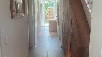 Ein Flur mit einer Wand in Holzoptik, einer Tür zum Balkon und einer Deckenleuchte.