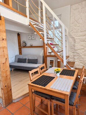 A modern interior with a wooden dining table, chairs, a sofa, and a staircase. - A Window to Porto - Corticeira Lovely House (Porto)