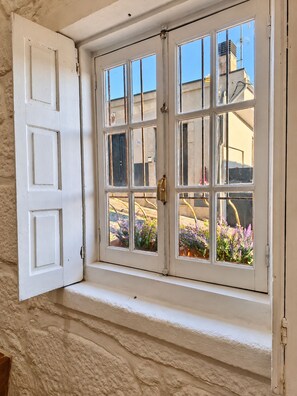 A white-framed window with multiple panes, a door to the left, and a view of a building with a chimney and outdoor plants. - A Window to Porto - Corticeira Lovely House (Porto)