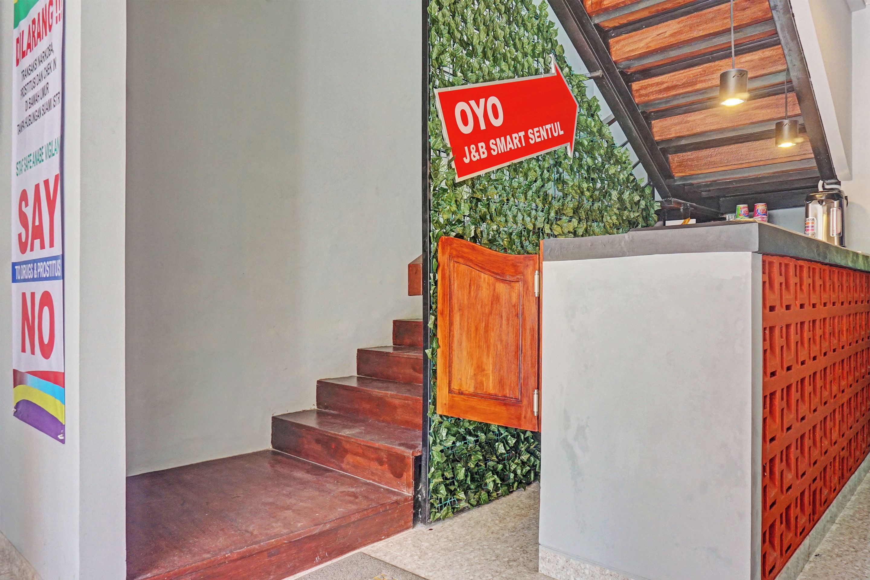 A staircase with a wooden handrail, a reception desk, and a green wall with a sign.