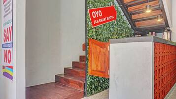 A staircase with a wooden handrail, a reception desk, and a green wall with a sign.