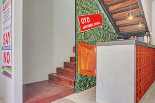 A staircase with a wooden handrail, a reception desk, and a green wall with a sign.