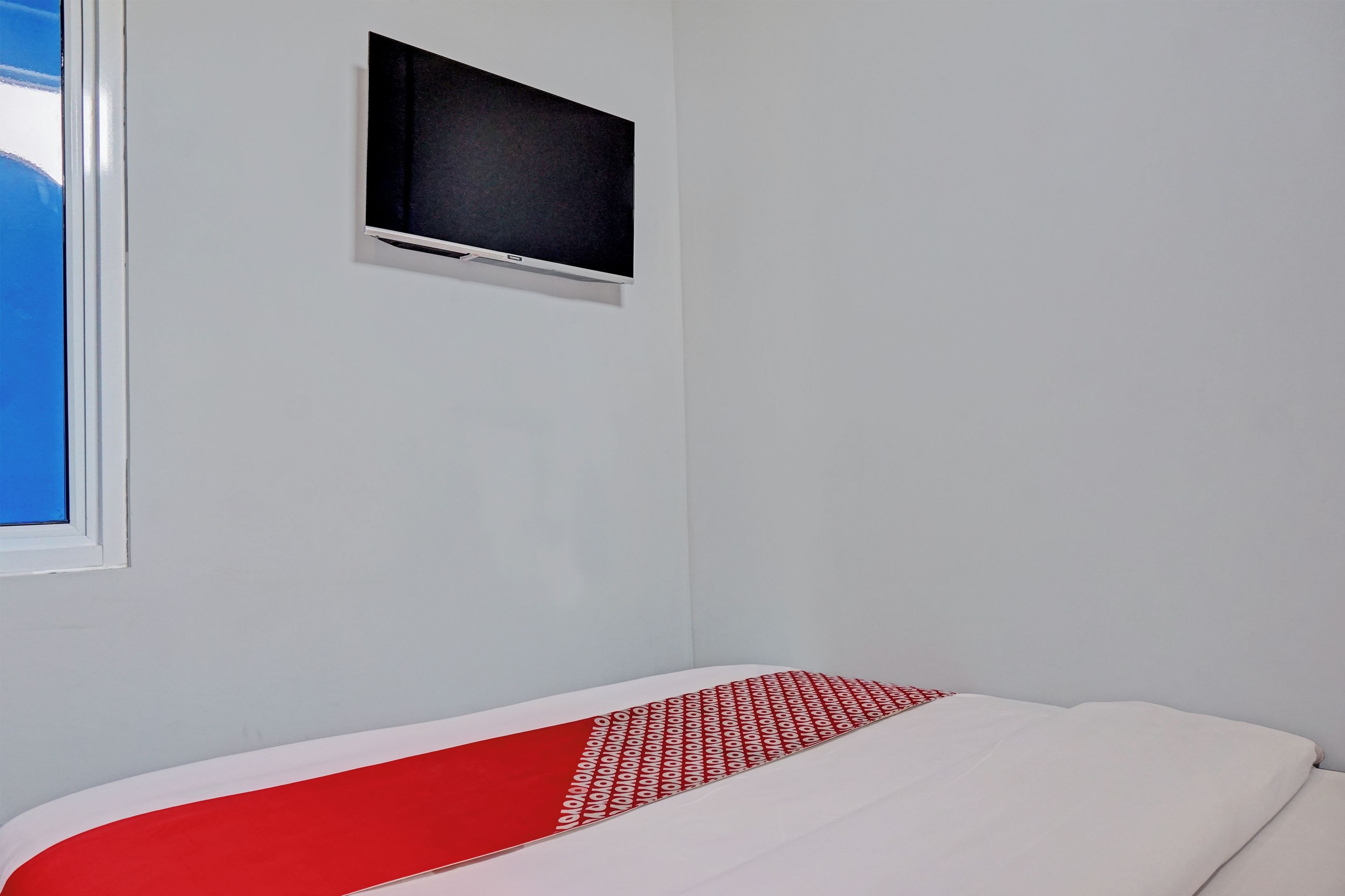 A room with a bed, a window, and a mounted television.