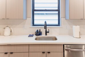 Una cocina moderna con un lavamanos de acero inoxidable, una tetera y un dispensador de toallas de papel.