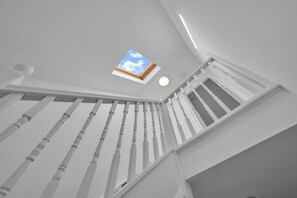 Een witte trap met dakraam en een ronde lamp.