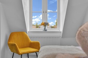 A room with a window, a yellow chair, and a bed. - Spacious 3-Bed Home | 4 Mins to Universal Studios | Parking & Fast WiFi (Marston Moretaine)