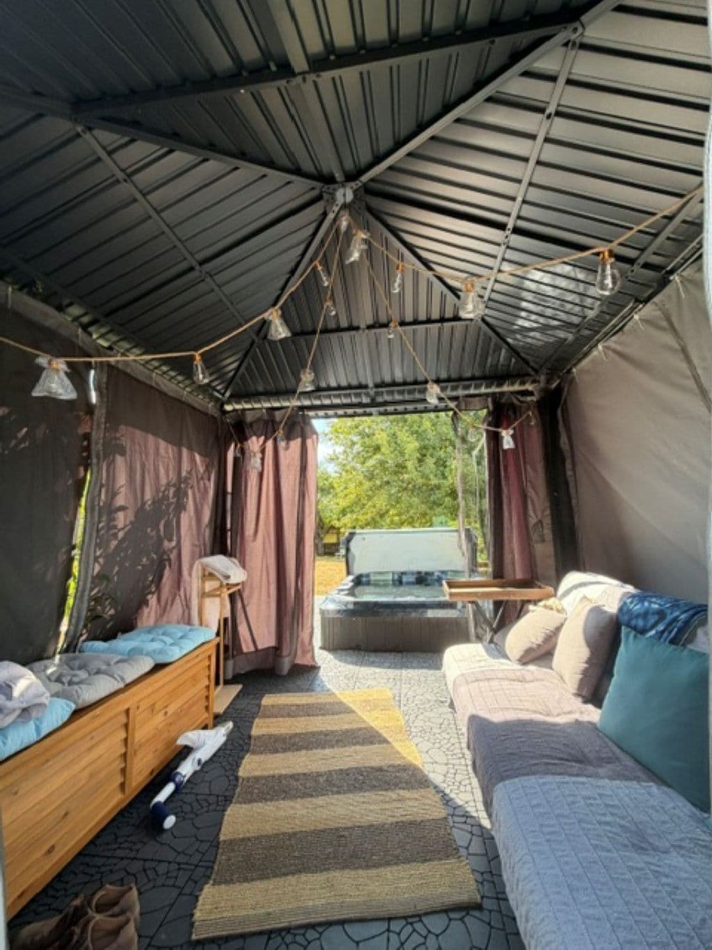 Een tentaccomodatie met een bed, een bank en een hottub.