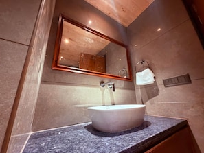 Un baño con un lavamanos ovalado grande, un espejo y un perchero para toallas.