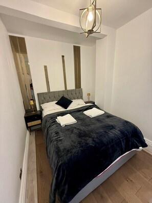 Un dormitorio moderno con una cama, mesitas de noche, una lámpara y un colgador de techo.