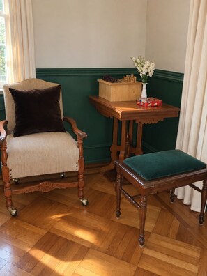 Ein Zimmer mit einem Holzstuhl und einem kleinen Tisch, beide mit gepolsterten Sitzflächen.