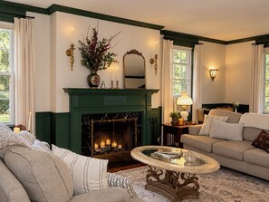 A room with a fireplace, green painted walls, a sofa, a coffee table, and a mirror. - Hopewell Creek Farm - Amish Country Farmhouse, Creek & Fall Color - Sleeps 8 (Lancaster)