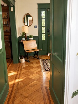 A hallway with a wooden bench, a potted plant, a mirror, and a door with a green frame. - Hopewell Creek Farm - Amish Country Farmhouse, Creek & Fall Color - Sleeps 8 (Lancaster)