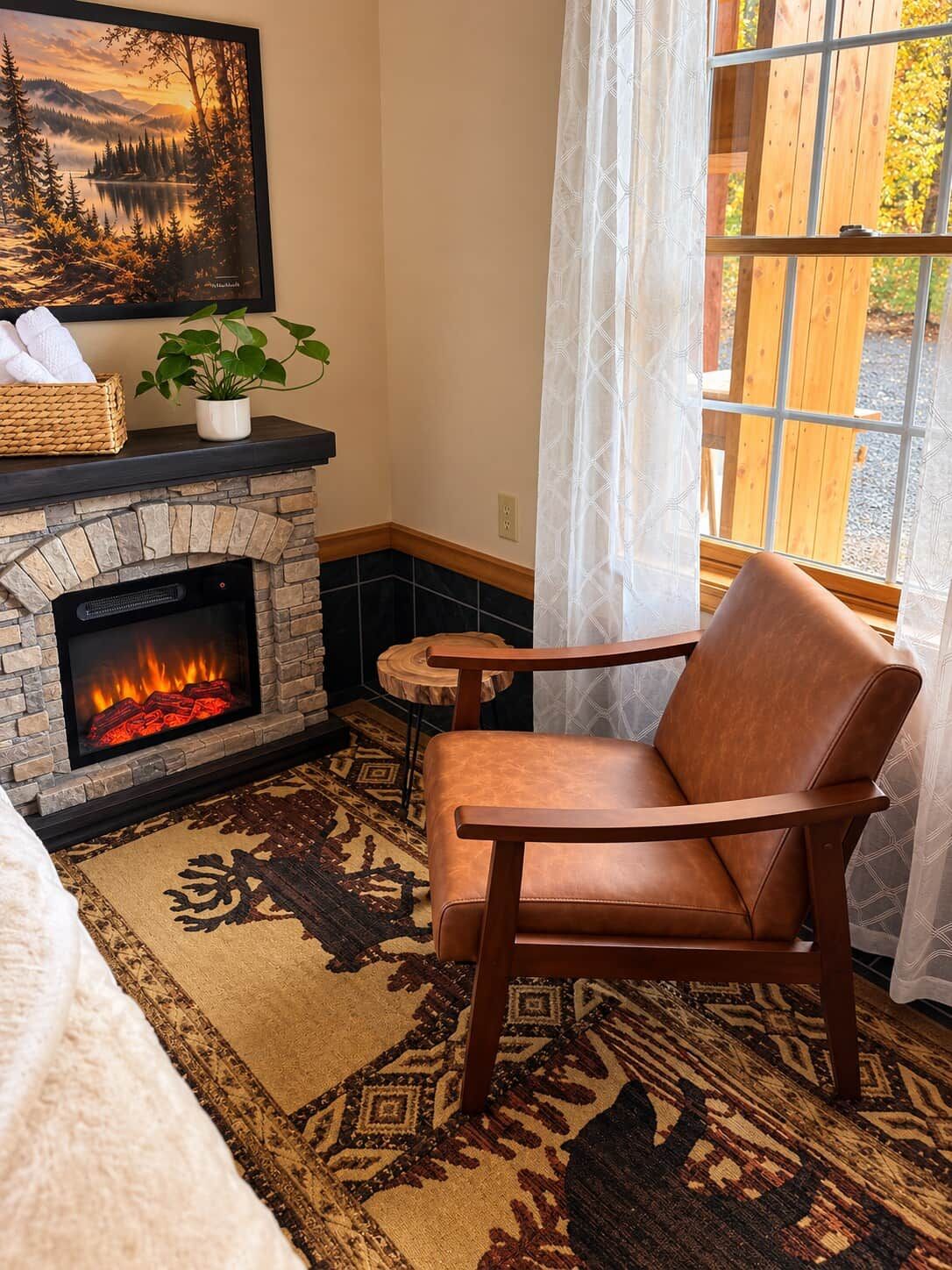 Una habitación acogedora con chimenea, un sillón de cuero, una alfombra y una ventana con cortinas.