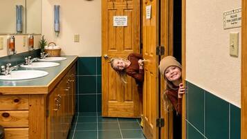 A bathroom with wooden cabinets, a sink, a mirror, and a clock on the wall.