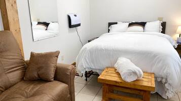 Ein Hotelzimmer mit einem Bett, einer Holzbank, einem braunen Sofa und einem an der Wand befestigten Luftreiniger.