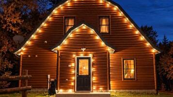 A wooden cabin with a front porch, a door, and windows.