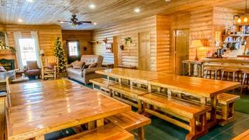 A rustic log cabin interior with wooden tables and benches, a sofa, and a Christmas tree.