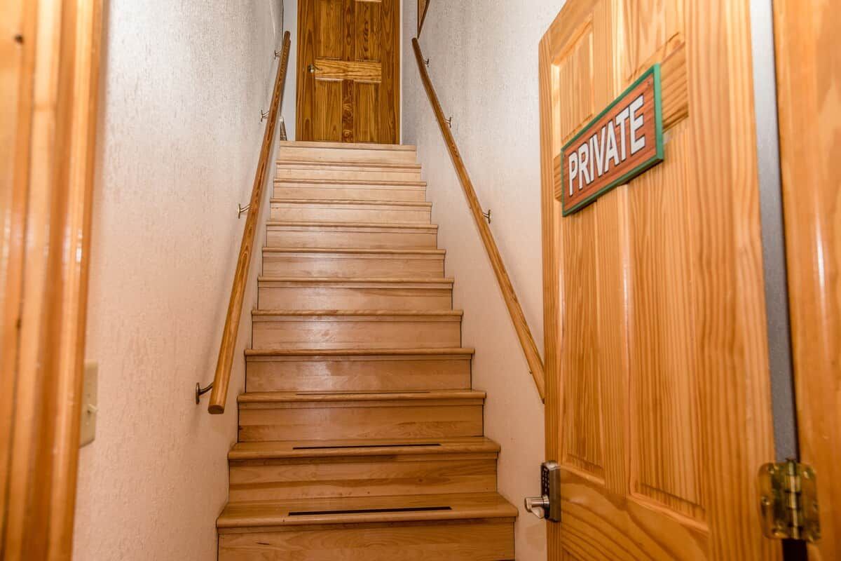 Una escalera de madera que lleva a una puerta privada.