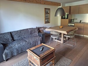 A modern living room with a sofa, a coffee table, and a dining area with a table and chairs. - Ski-in/ski-out apartment with Mont Blanc view (Bourg-Saint-Maurice)