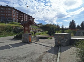 A gated entrance with a stone structure, a sign indicating 'Les Alpages du Chantel', and a multi-story building in the background. - Ski-in/ski-out apartment with Mont Blanc view (Bourg-Saint-Maurice)
