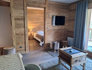 A wooden interior with a bed, a television, a small table, and a window with curtains. - Ski-in/ski-out apartment with Mont Blanc view (Bourg-Saint-Maurice)