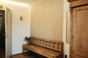 A wooden bench with vertical slats, a wooden door, and a wall-mounted light fixture. - Hintergruberhof Vacation Rental (Oberaudorf)