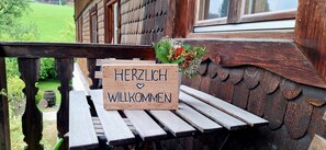 A wooden sign with the text 'HERZLICH WILKOMMEN' on a bench outside a building with a rustic design. - Hintergruberhof Vacation Rental (Oberaudorf)
