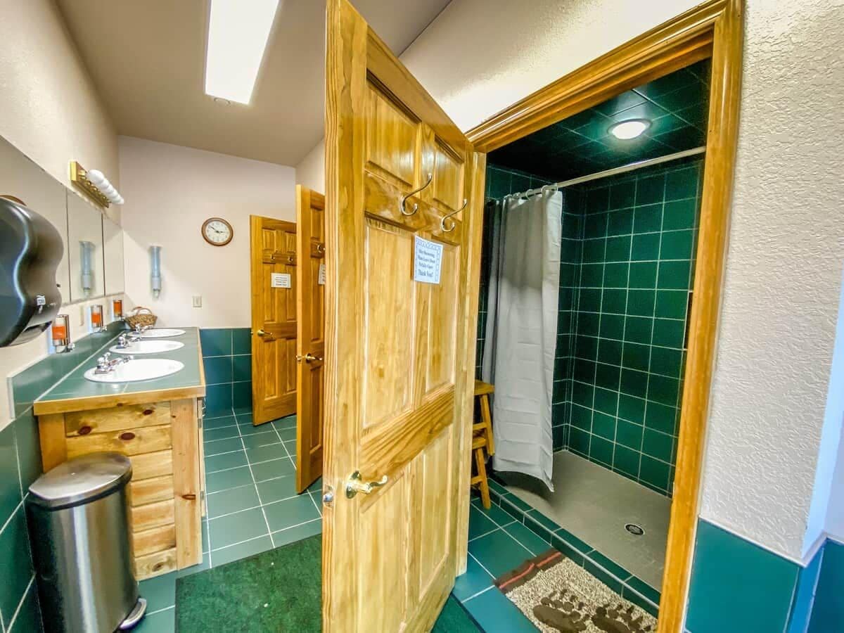 Ein Badezimmer mit zwei Waschbecken, einer Dusche und einer Holztür.