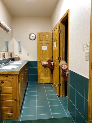Un baño con armarios de madera, un lavabo y un reloj en la pared.