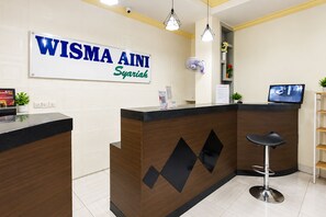 A reception desk with a sign reading 'WISMA AINI Syariah' and a computer monitor on the counter. - Hotel O near UIN Raden Intan (Bandar Lampung)