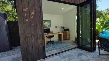 A room with a desk, chair, and a glass door leading outside.