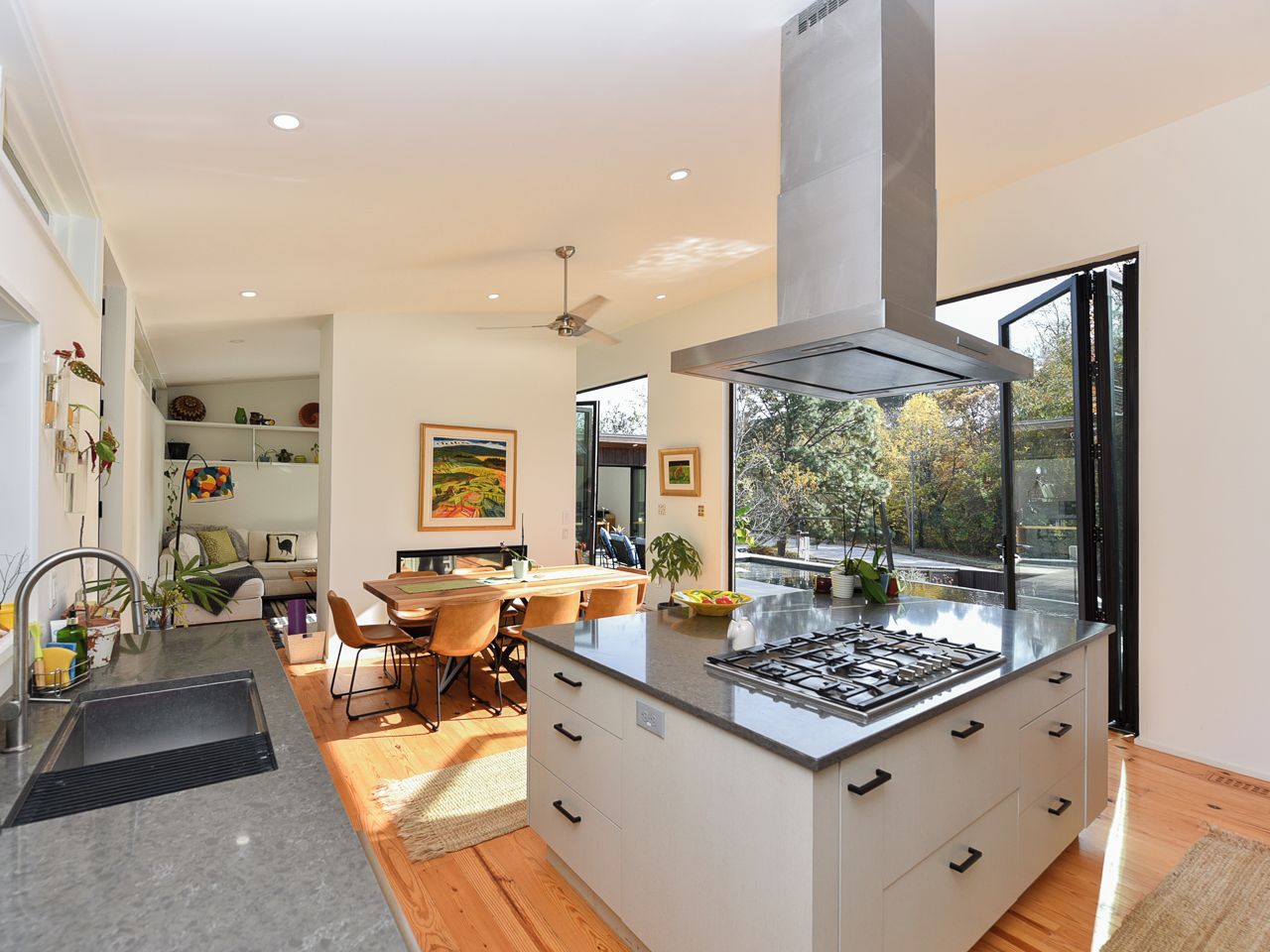 A modern kitchen with a central island, a dining area, and a view of the outdoors.