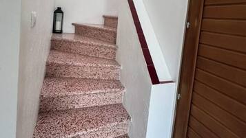 Eine Treppe mit hölzernem Geländer, einer an der Wand befestigten Uhr und einer an die Wand gelehnten Gitarre.