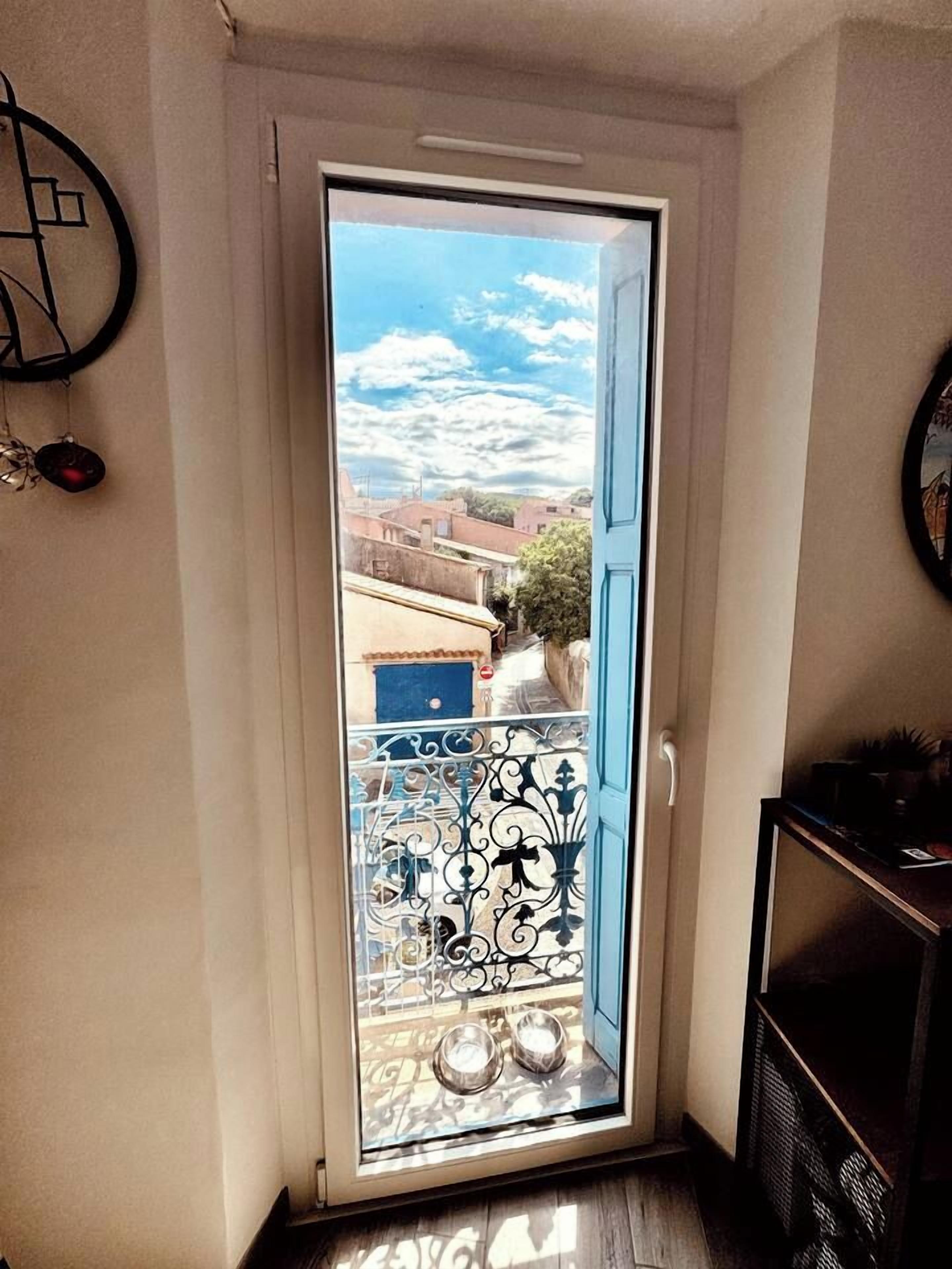 Eine Tür führt zu einem Balkon mit Blick auf Gebäude und einen klaren Himmel.