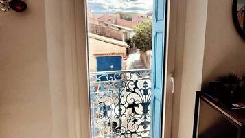Eine Tür führt zu einem Balkon mit Blick auf Gebäude und einen klaren Himmel.