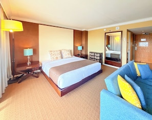 A hotel room with a large bed, a sofa, a desk, and a mirror. - @ Marbella Lane - Dreamy Oceanview Lanai Waikiki (Honolulu)