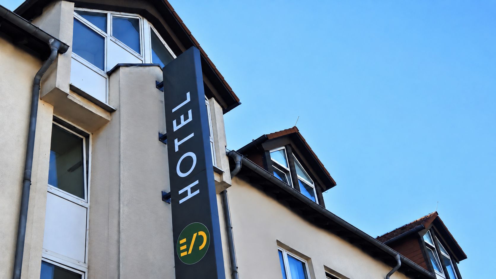A hotel sign with a logo and the word 'HOTEL' on a building corner.