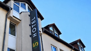 Un letrero de hotel con un logotipo y la palabra 'HOTEL' en una esquina del edificio.