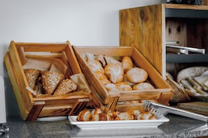 Variedad de panes y pasteles en cajas de madera sobre una encimera.