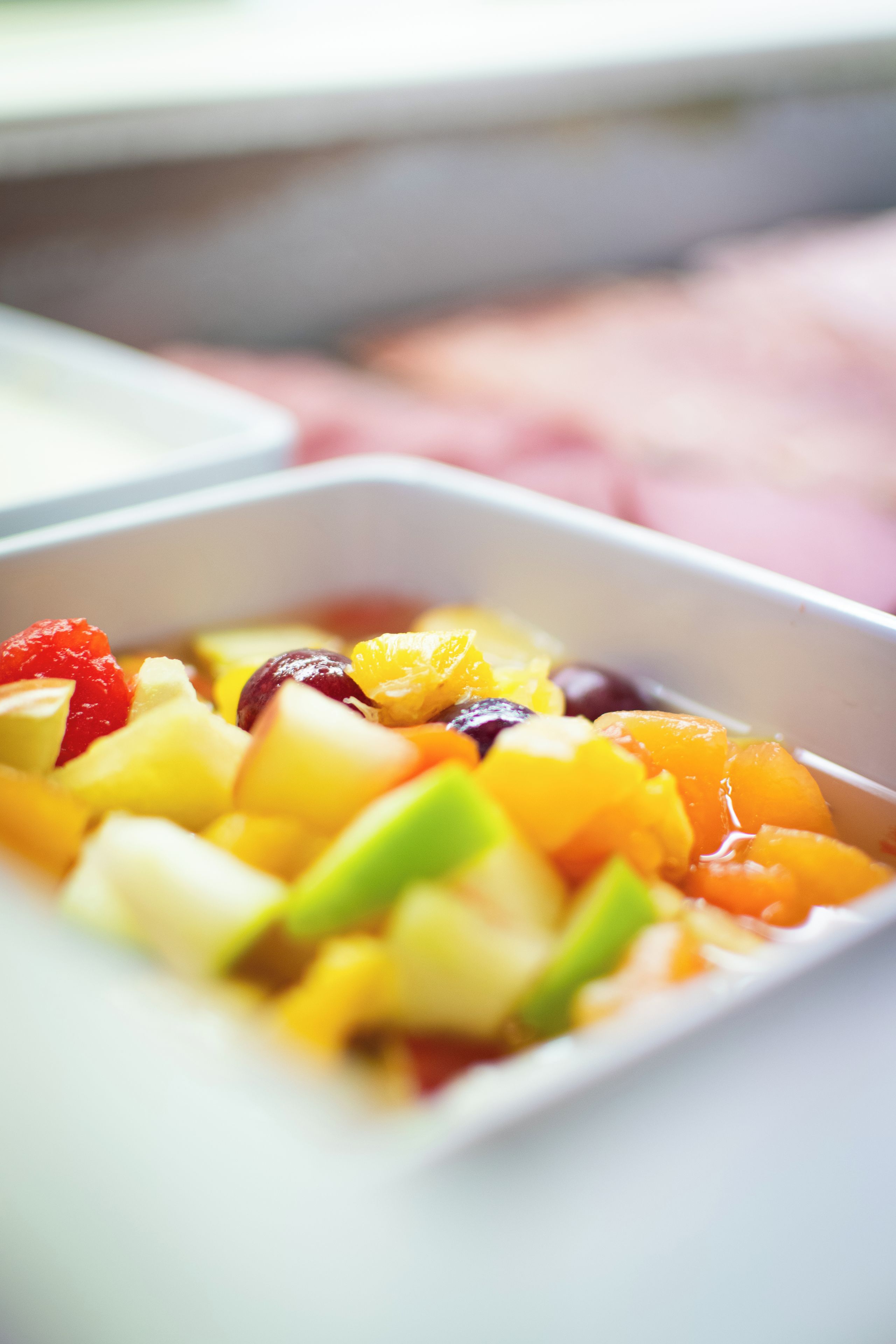A close-up of a fruit salad in a white bowl.