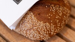 A loaf of bread with sesame seeds on a wooden surface.