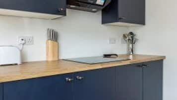 Una cocina con armarios azul oscuro, encimera de madera, microondas y un juego de cuchillos.
