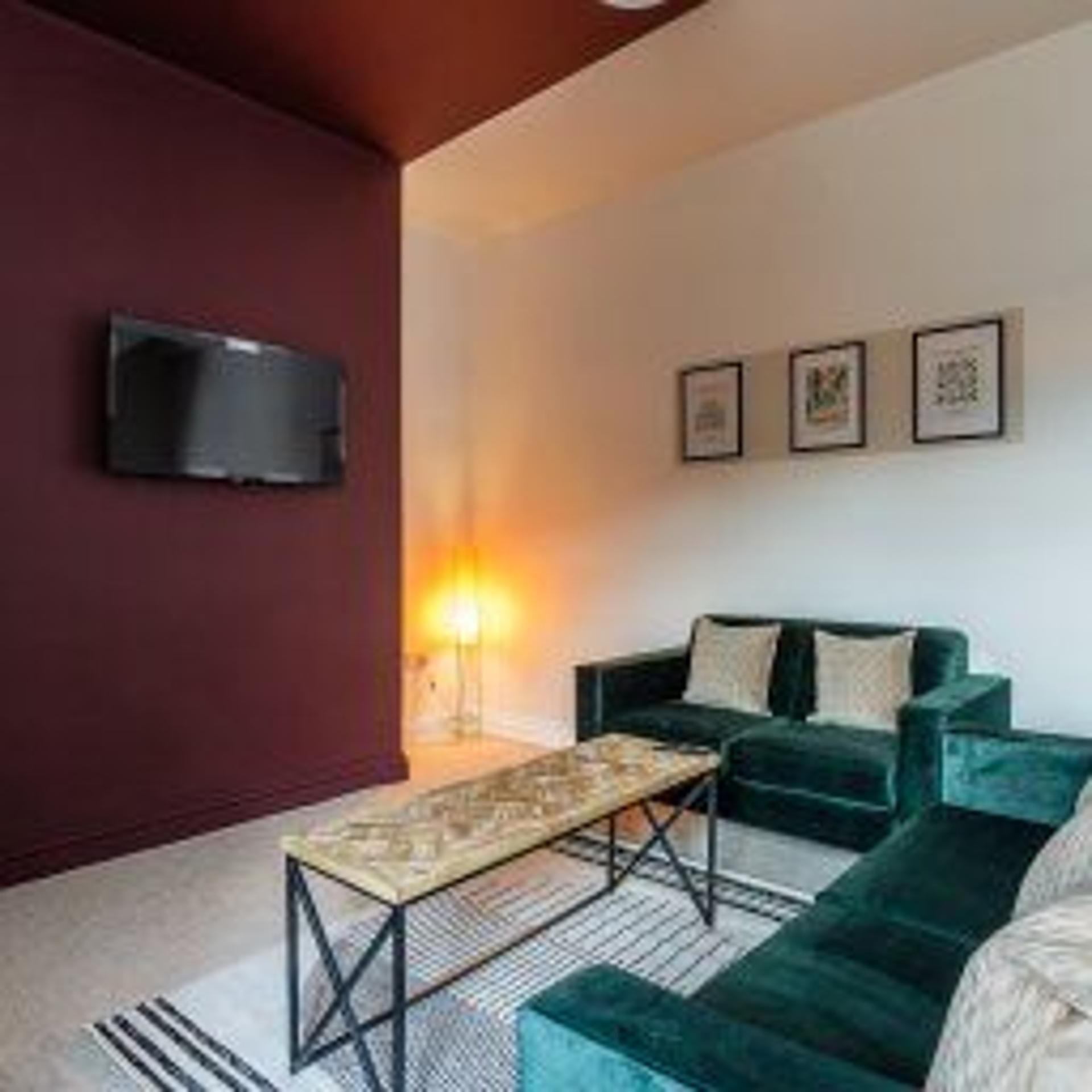 Una sala de estar moderna con un sofá, una mesa de centro y un televisor de pantalla plana montado en la pared.