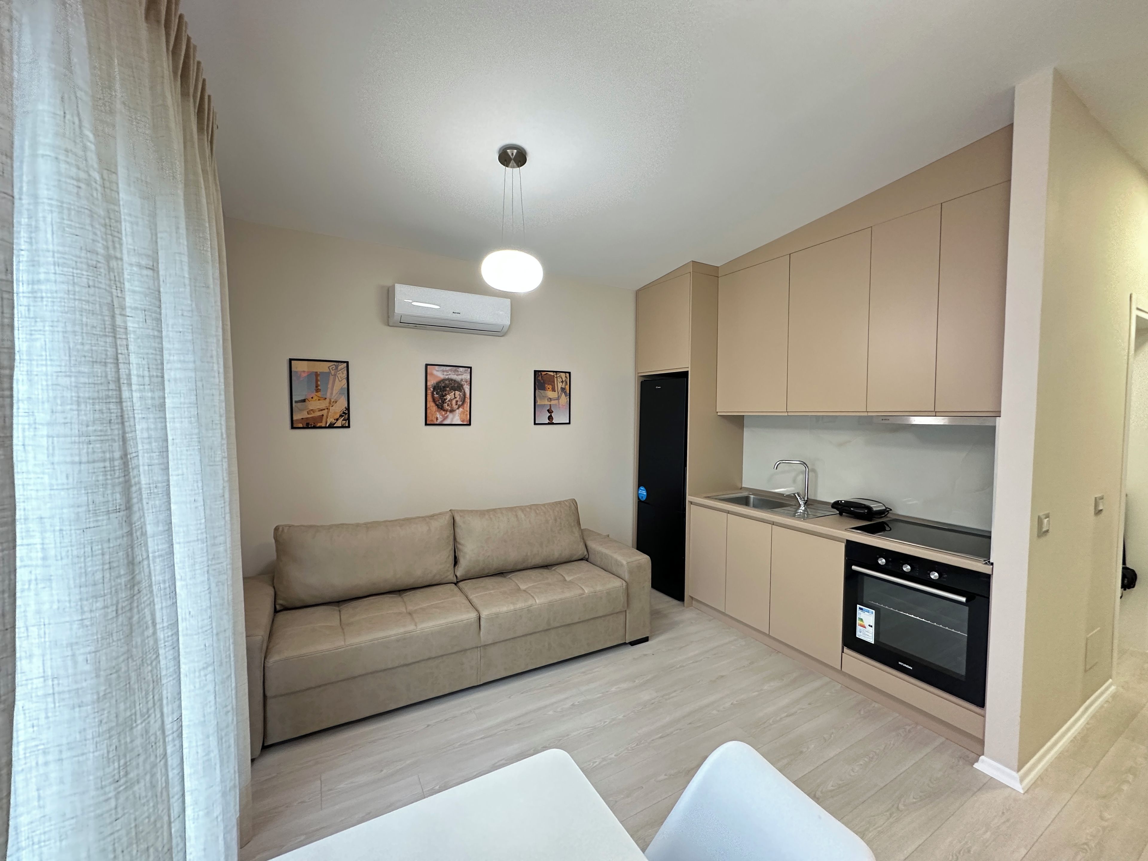 Un apartamento moderno con sofá, kitchenette y obras de arte en las paredes.