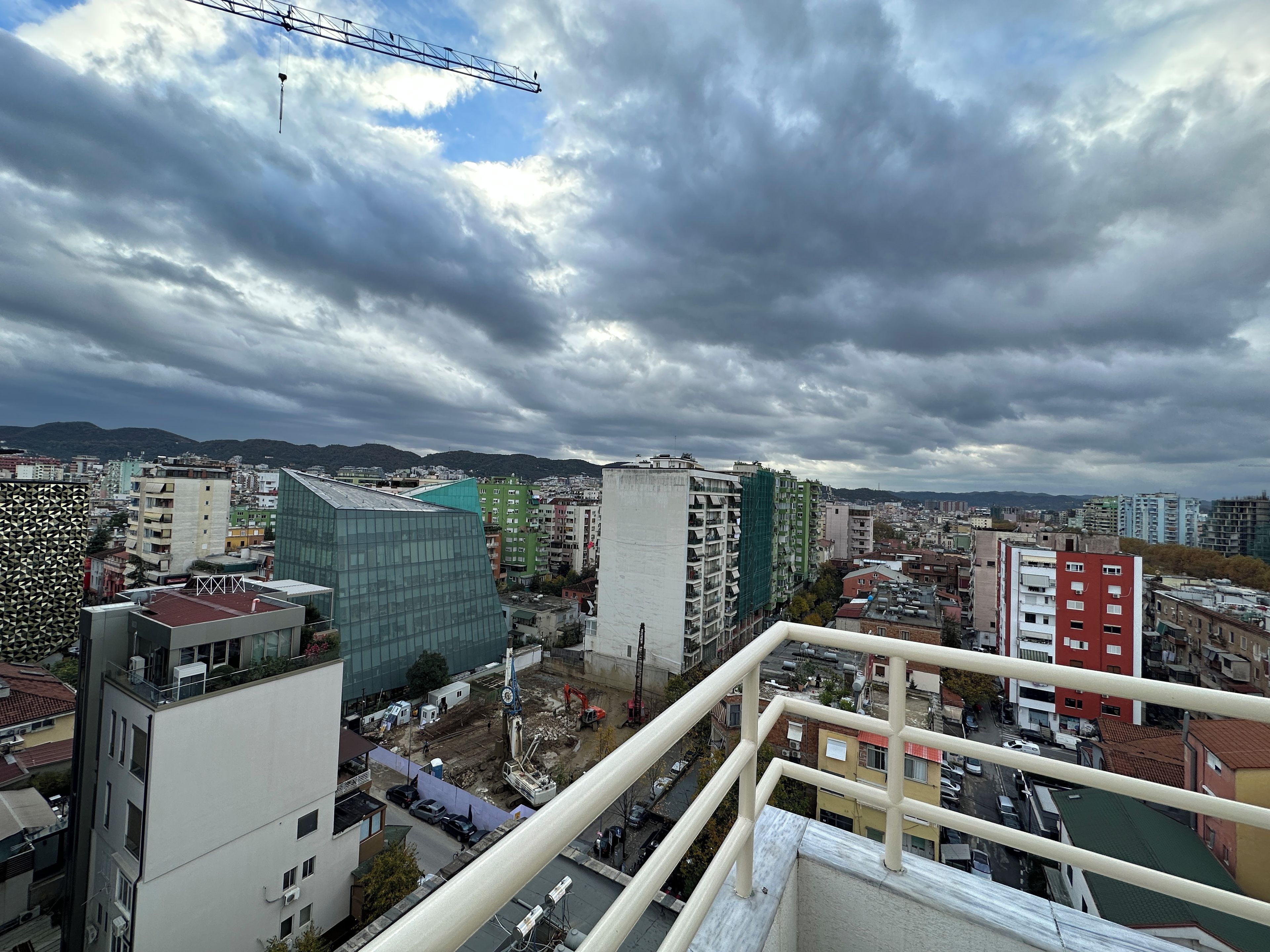 A cityscape with various buildings, including a distinctive green glass structure and a red building.