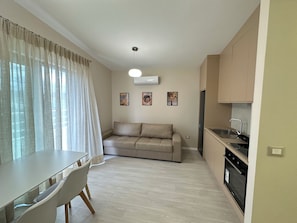 Un espacio habitable compacto con mesa de comedor, sofá, kitchenette y lámpara de techo.
