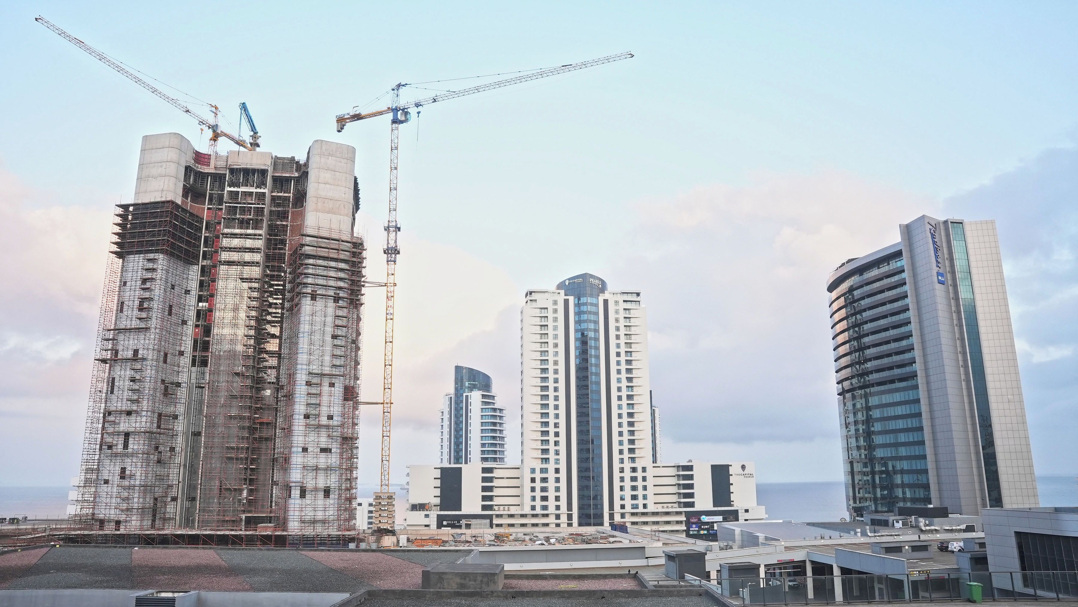 A construction site with a large building under scaffolding and a crane.