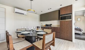A modern kitchen with dark wooden cabinets, a built-in oven, and a dining area with a round table and chairs. - AN EXCEPTIONAL CENTRAL LOCATION FOR AN UNFORGETTABLE PARISIAN STAY-RUE DE RIVOLI (Paris)